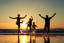 Silhouette Of Happy Family Who Standing On The Beach At The Suns