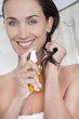 femme souriant qui applique de l'huile sur les pointes de ses cheveux
