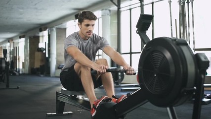 Poster - Handsome man doing exercise on fitness machine in gym