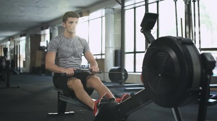 Poster - Handsome man doing exercise on fitness machine in gym