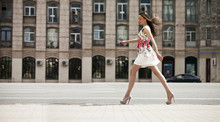 Young Beautiful Brunette Woman In White Flowers Dress Walking On