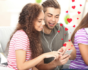 Wall Mural - Teenager couple listening to music with mobile phone on a sofa