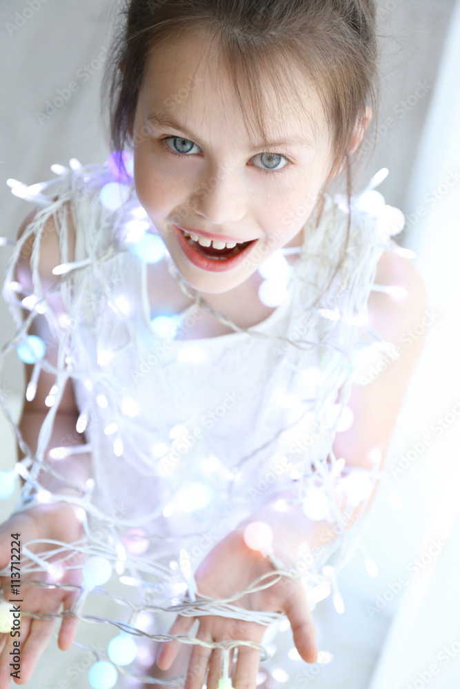 Little girl in light garland at home