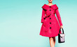 © MoustacheGirl - Colorful red trench coat woman with black leather handbag isolated on light blue background. Vintage retro mood fashion image.