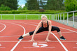 © michaelheim - Athletic woman doing straddle stretches on track