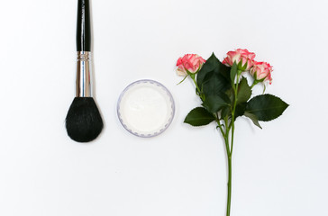 Composition with makeup cosmetics, brushes, shadoes and flowers on white background