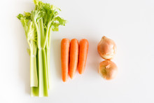 High Angle View Of Celery, Carrots And Onions On A White Table