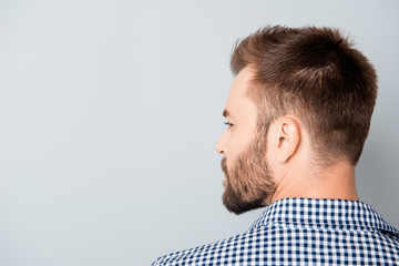 Back view of young bearded brunet man on gray background