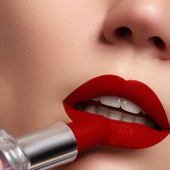 Wall Mural - Extreme close up on model applying dark red lipstick. Make-up