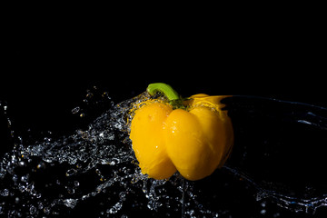 Yellow paprika with water splash on black