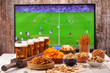 Beer and snacks set on football match tv background
