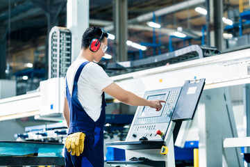 Worker entering data in CNC machine at factory