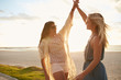 © Jacob Lund - Two young women giving high five on the beach