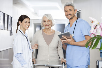 Poster - Physiotherapists Standing With Female Patient Using Walker