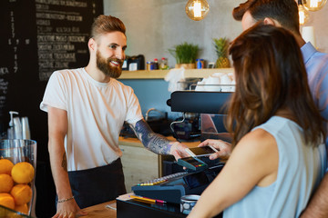 Wall Mural - Couple making payment with smartphone at coffe shop