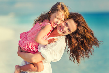portrait of happy mother and little daughter on sunny beach