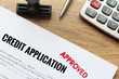Approved credit application form lay down on wooden desk with rubber