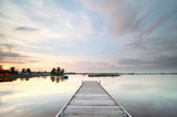 Fototapeta Pomosty - wooden pier on big lake at sunset