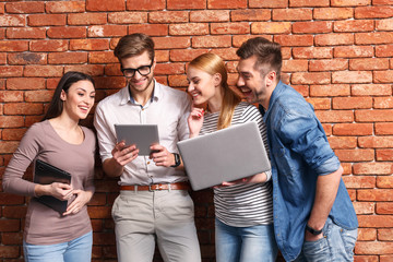 Wall Mural - Happy four friends using modern gadgets