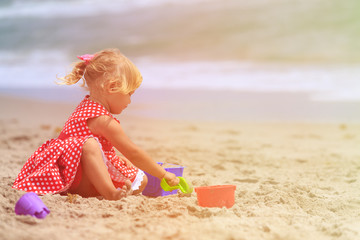 cute little girl play with sand on beach