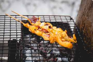 Two stick of Squids were grilling  on a stove