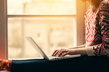 Woman with laptop on the window sill.