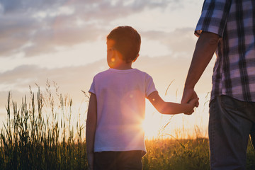 Canvas Print - Father and son playing at the park at the sunset time.