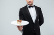 © Drobot Dean - Waiter in tuxedo holding piece of cake on plate