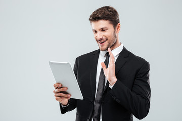 Poster - Smiling young businessman using tablet and making video conference