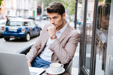 Wall Mural - Serious businessman using modern laptop in coffee shop