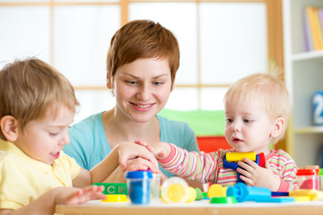 Wall Mural - mother teaches her children to work with colorful play clay toys