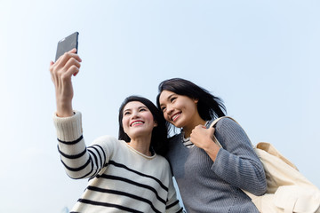 Wall Mural - Two girls using mobile phone to take photo