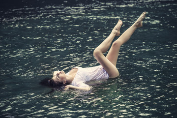 Young beautiful woman enjoys the lake with turquoise clear water