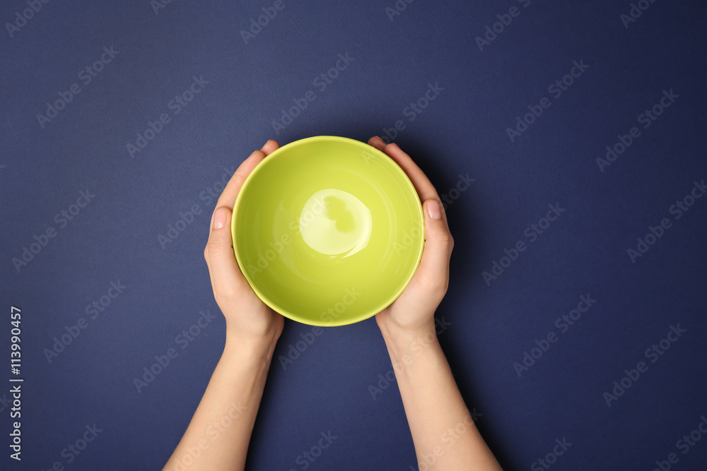 Female hands and empty bowl on blue background