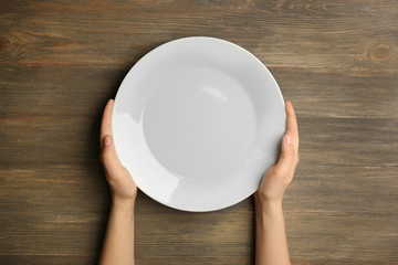 Canvas Print - Female hands and empty plate on wooden background