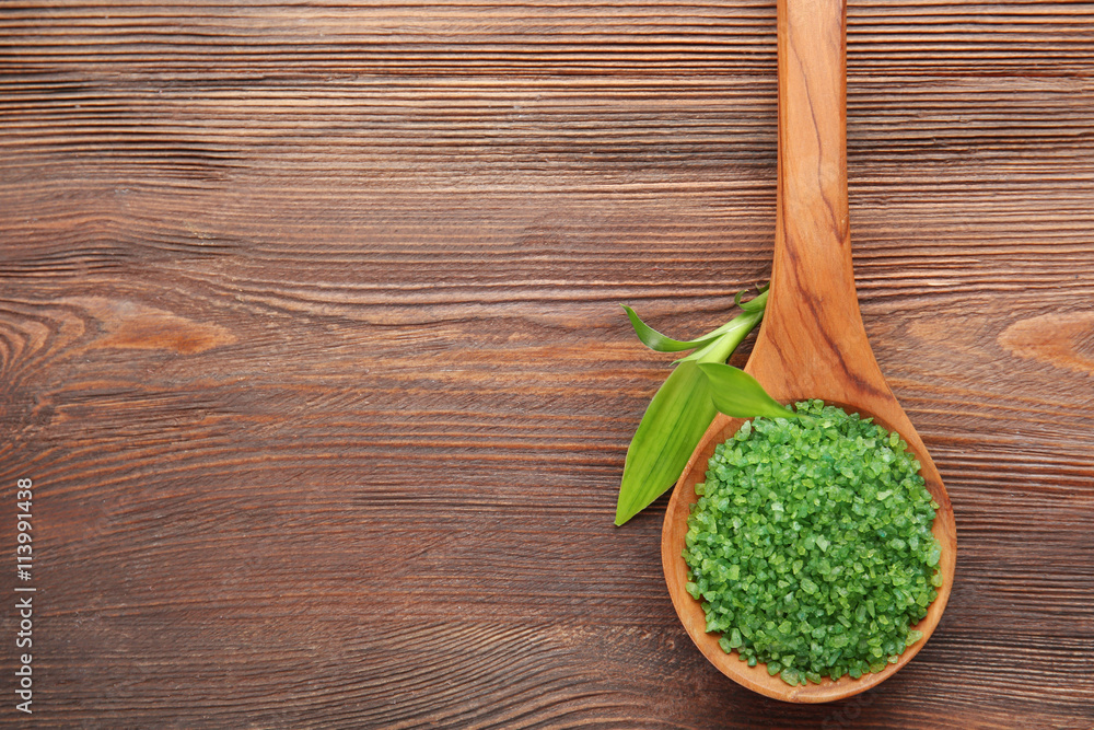 Spoon with sea salt on wooden background