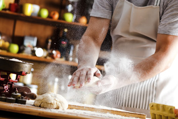 Wall Mural - Male baker prepares bread. Male baker slaps on dough. Making bread.