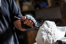 Close Up Of Senior Sculptor Hands Working On His Marble Sculpture In His Workshop With Hammer And Chisel