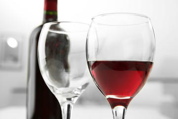 Canvas Print - Glass of red wine with bottle on blurred interior background