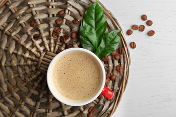 Poster - Cup of coffee with beans and leaves on wicker background