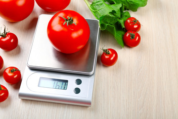 Wall Mural - Tomatoes with digital kitchen scales on wooden background