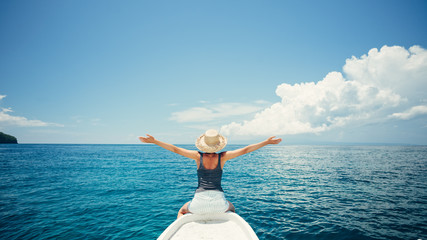 Young and happy woman traveling on the boat in the ocean