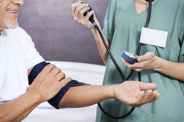 Poster - Midsection Of Nurse Checking Blood Pressure Of Senior Patient