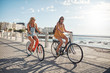 © Jacob Lund - Happy female friends riding bicycles on the seaside road