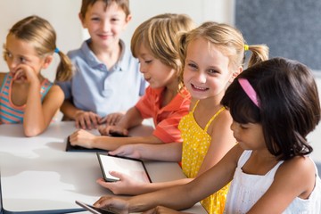 Smiling children using digital tablets