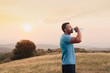 © chrisgraphics - Athletic man in his 30s resting and drinking water from a bottle while sitting down outdoor