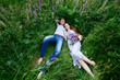man and woman embracing lying in grass on a meadow with  bouquet of lupines