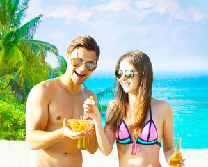 Wall Mural - Happy young couple drinking beer at the beach on resort