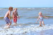 Cute active children playing and jumping in the sea. Happy siblings or friends enjoying summer holidays on a sunny day. Family with young kids on vacation at the North Sea coast.