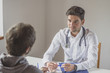 © GENETTICA - Young doctor with stethoscope pays attention to his patient in his office.